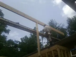 Carpenter setting a ridge beam over a new addition frame — Ice Dam Removal by Roofing Brothers in Aquebogue