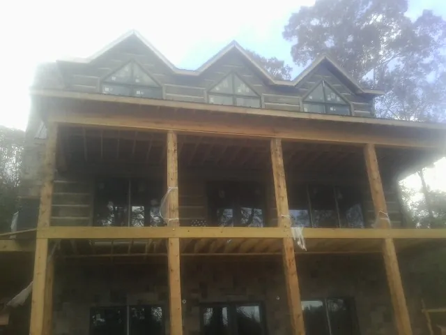 Dormers and porch framing on a large log home under construction — Roof Coating work by our crew in Aquebogue