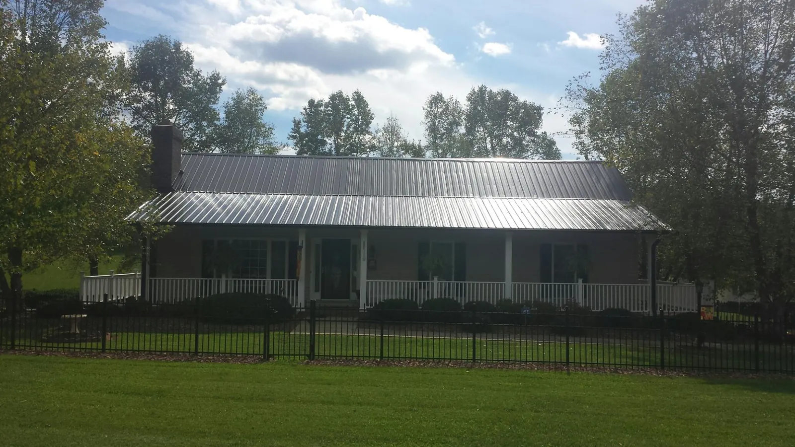 Gray metal roof on a brick ranch with a full width front porch — Gutter Guard Installation work by our crew in Aquebogue