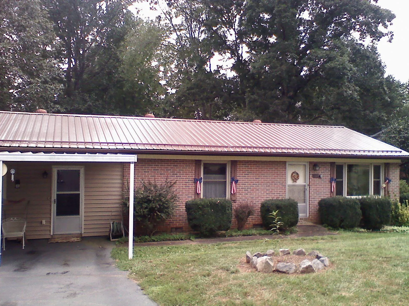 Bronze metal roof and carport on a brick ranch home — Roof Repair work by our crew in Aquebogue