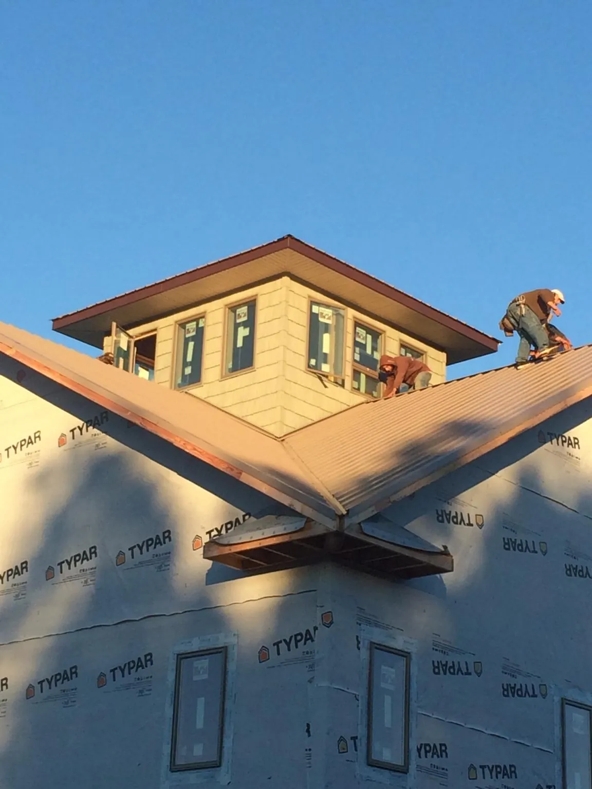 Roofers working around a rooftop cupola on a new metal roof at sunset — Roof Waterproofing in Aquebogue by Roofing Brothers